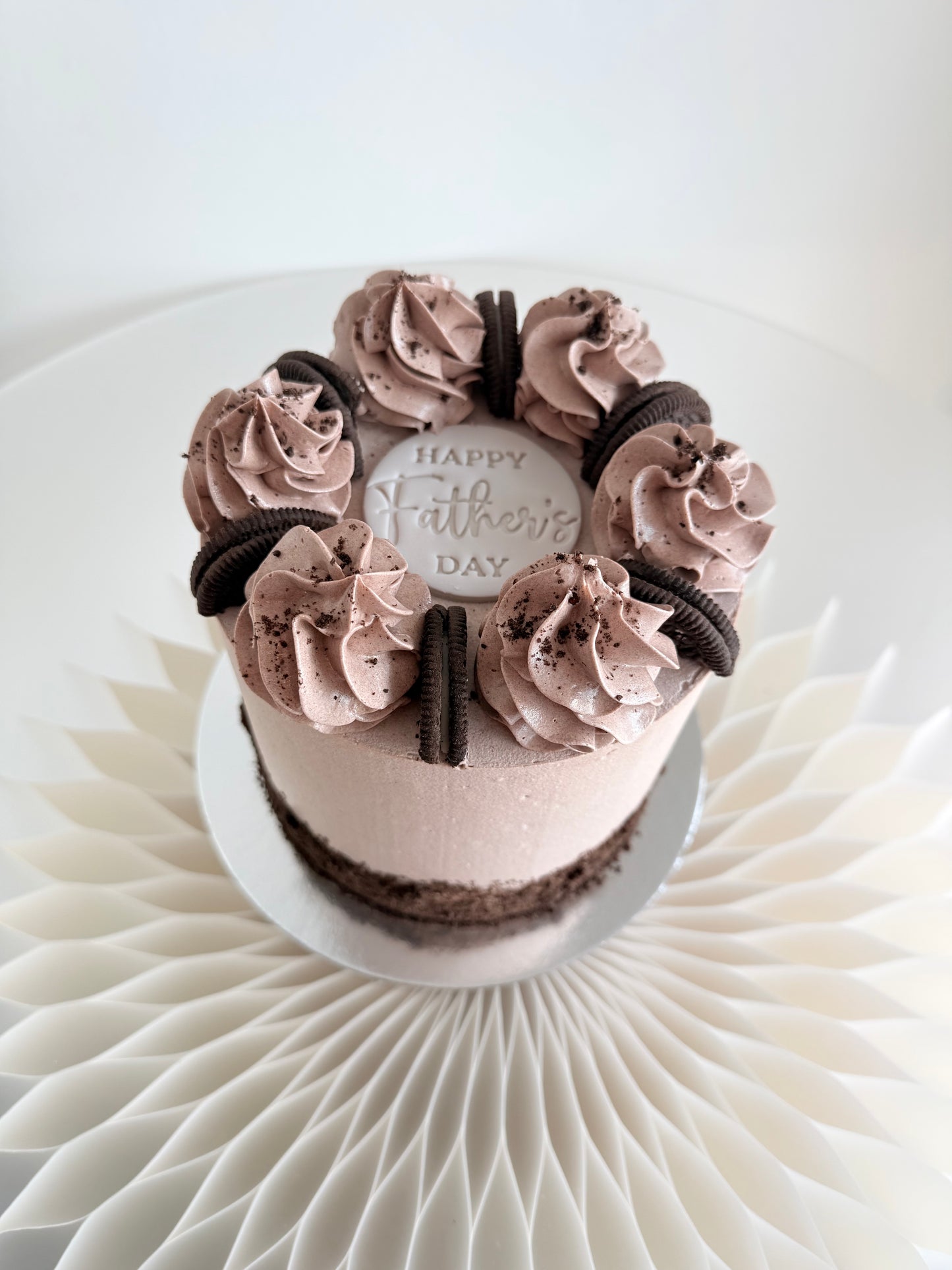 Side view of the 6 inch Father's Day cookies and cream cake on a white stand