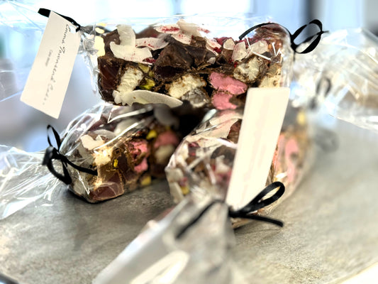 Rocky road, Packaged handmade chocolates with visible pieces of marshmallows, pistachios, and coconut flakes.