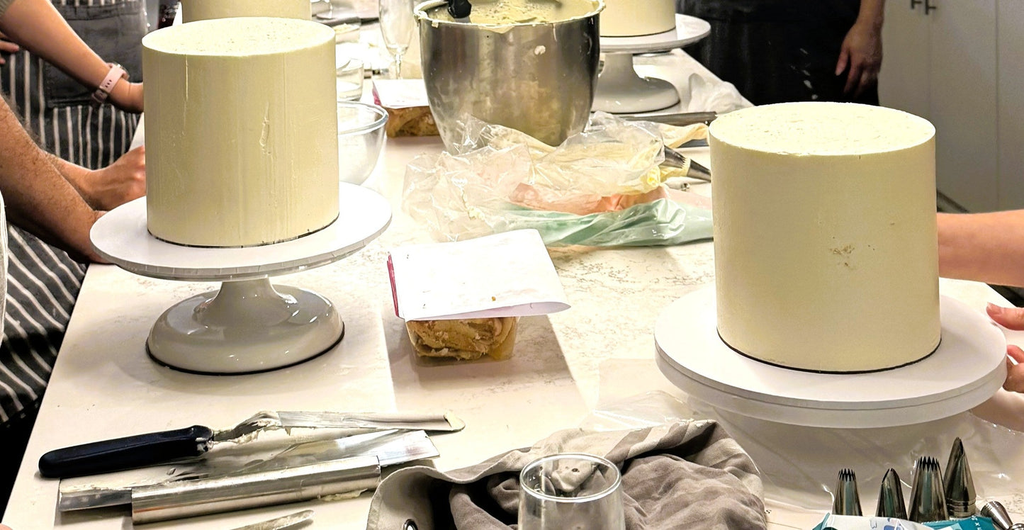 Row of buttercream covered cakes on stands during the masterclass
