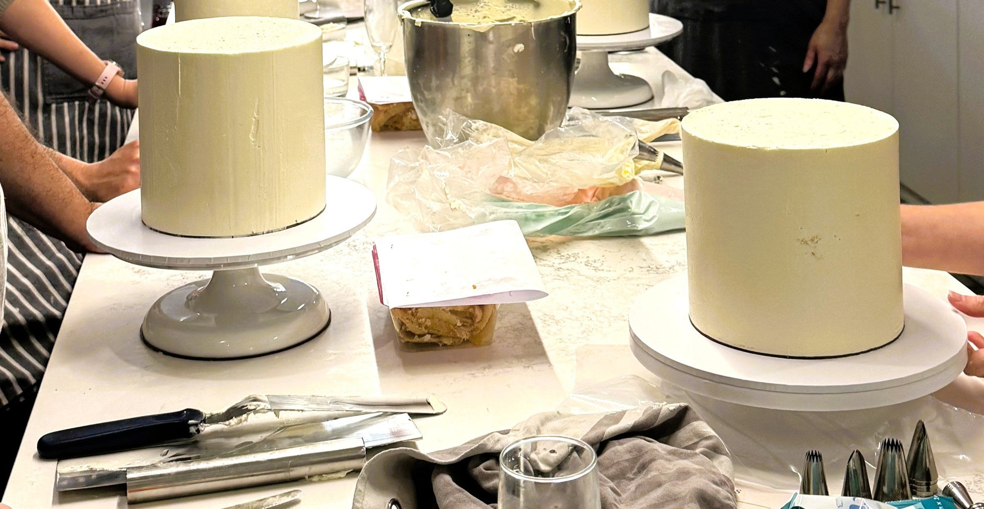Row of buttercream covered cakes on stands during the masterclass