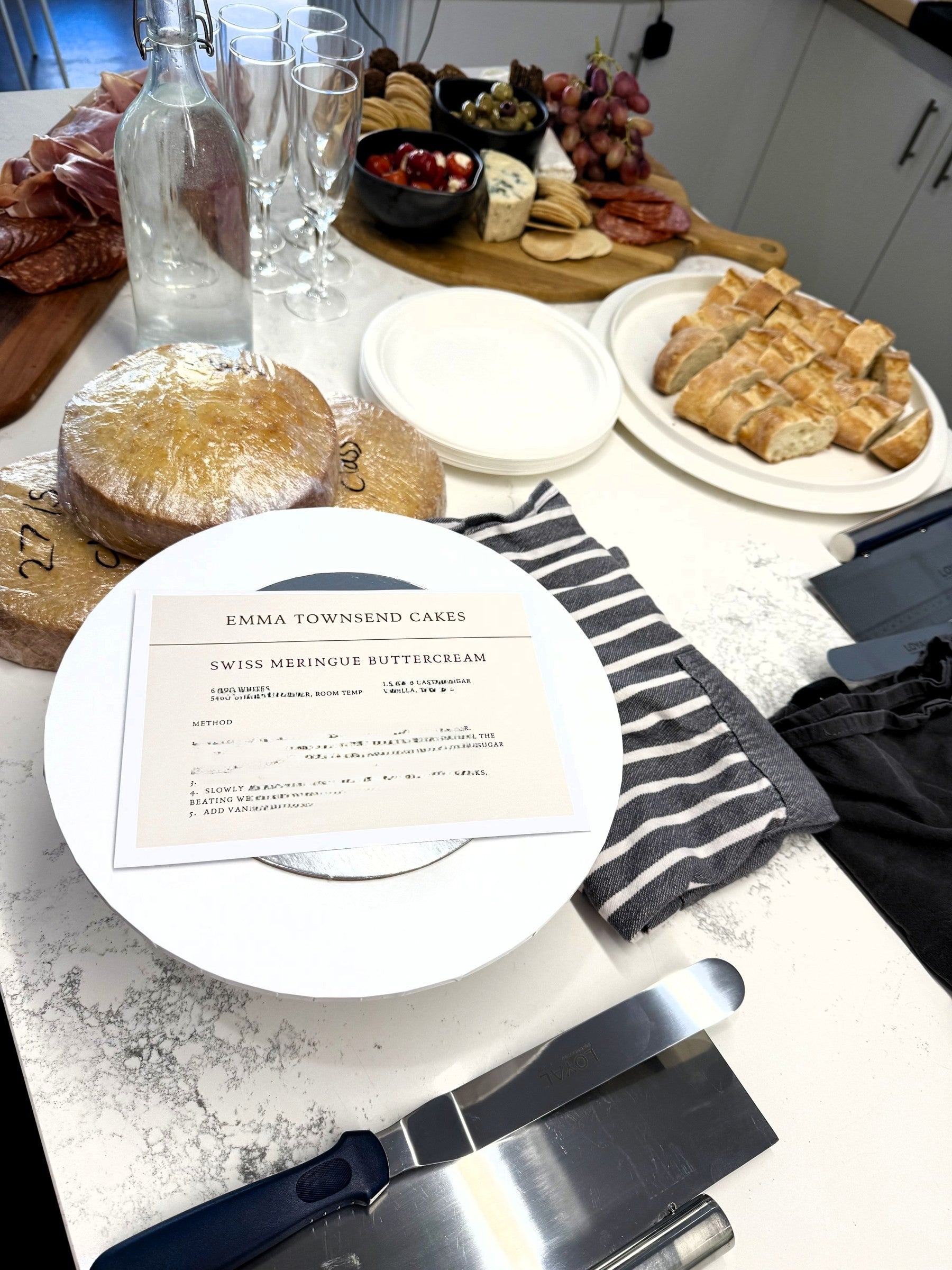 Swiss meringue buttercream recipe card beside the class grazing board and bubbles