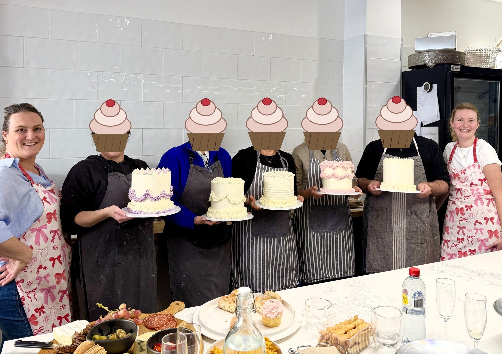 Buttercream masterclass guests holding the three layer cakes they decorated