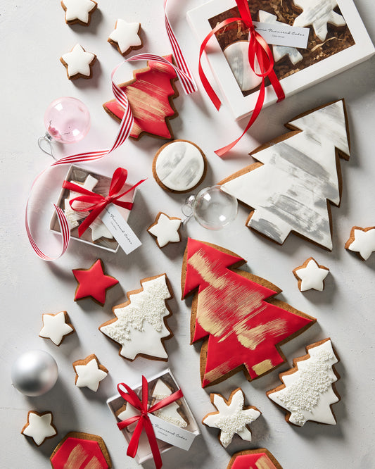 Christmas gingerbread cookie boxes tied with red ribbon among iced gingerbread trees and stars